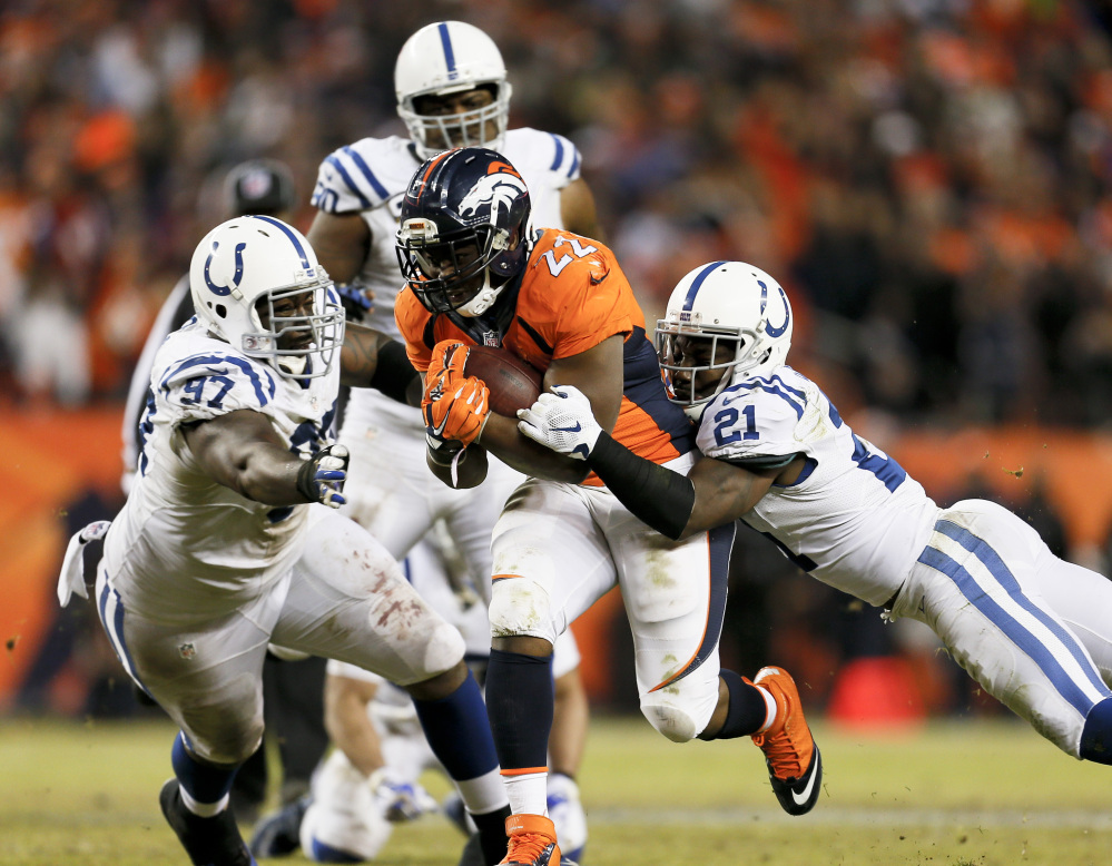 Denver Broncos running back C.J. Anderson, middle, converts a fourth down run for a first down as Indianapolis Colts cornerback Vontae Davis (21) and Arthur Jones (97) tackle him Sunday in Denver. The Associated Press