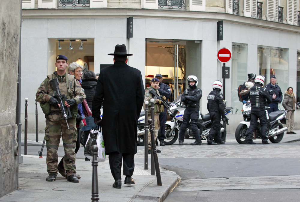 Police officers and French army soldiers patrol Rue des Rosiers in the heart of the Jewish quarter in Paris on Monday. France ordered 10,000 troops into the streets to protect sensitive sites after three days of bloodshed and terror, amid the hunt for accomplices to the attacks that left 17 people and the three gunmen dead.