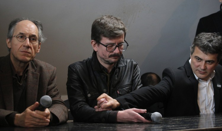 The new chief editor of French satirical magazine Charlie Hebdo, Gerard Biard, left, and columnist Patrick Pelloux, right, comfort Cartoonist Renald Luzier, known as Luz  during a press conference in Paris, France, Tuesday.