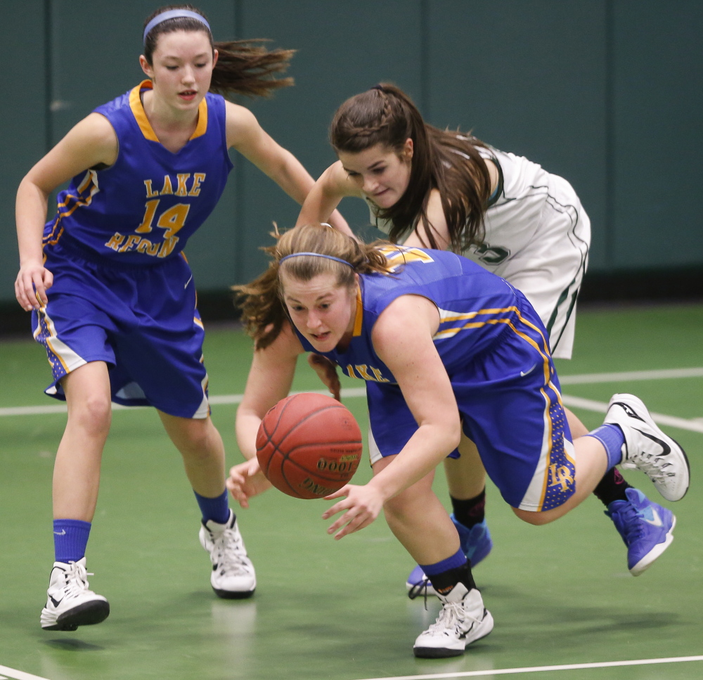 Spencer True of Lake Region dives for the basketball ahead of her teammate, Chandler True, and Elspeth Olney of Waynflete during Lake Region’s 52-29 victory Wednesday in a Western Maine Conference game.