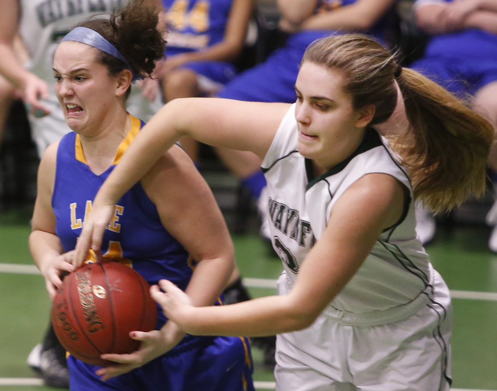 Dana Peirce of Waynflete, right, attempts to pry the ball from Melody Millett of Lake Region during their Western Maine Conference girls’ basketball game Wednesday. Lake Region, the defending Class B state champ, defeated its Class C opponent, 52-29.