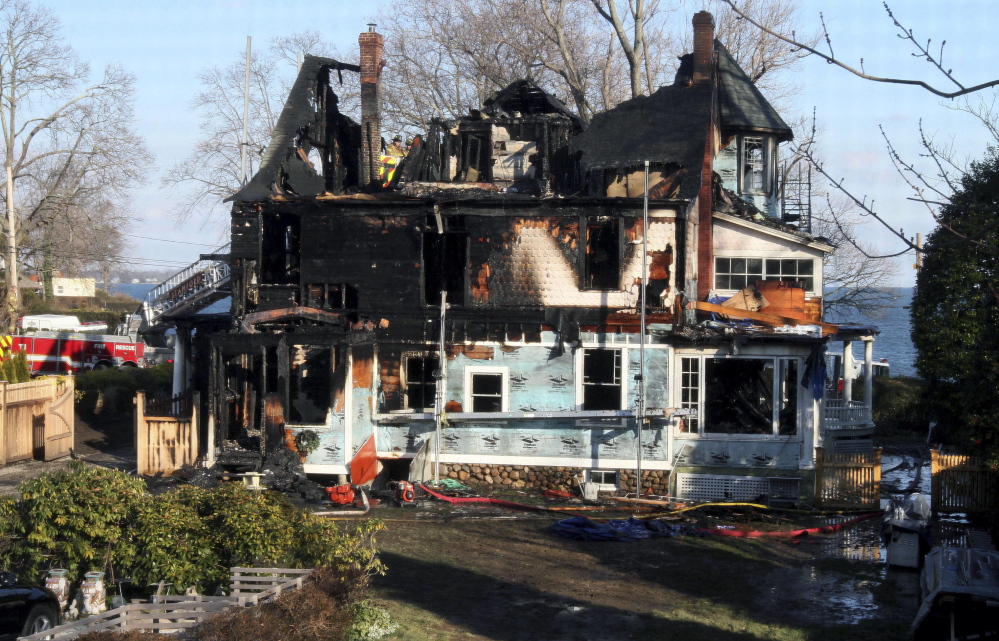 Firefighters investigate the home in Stamford, Conn., where a Christmas Day 2011 fire killed three young girls and two of their grandparents.