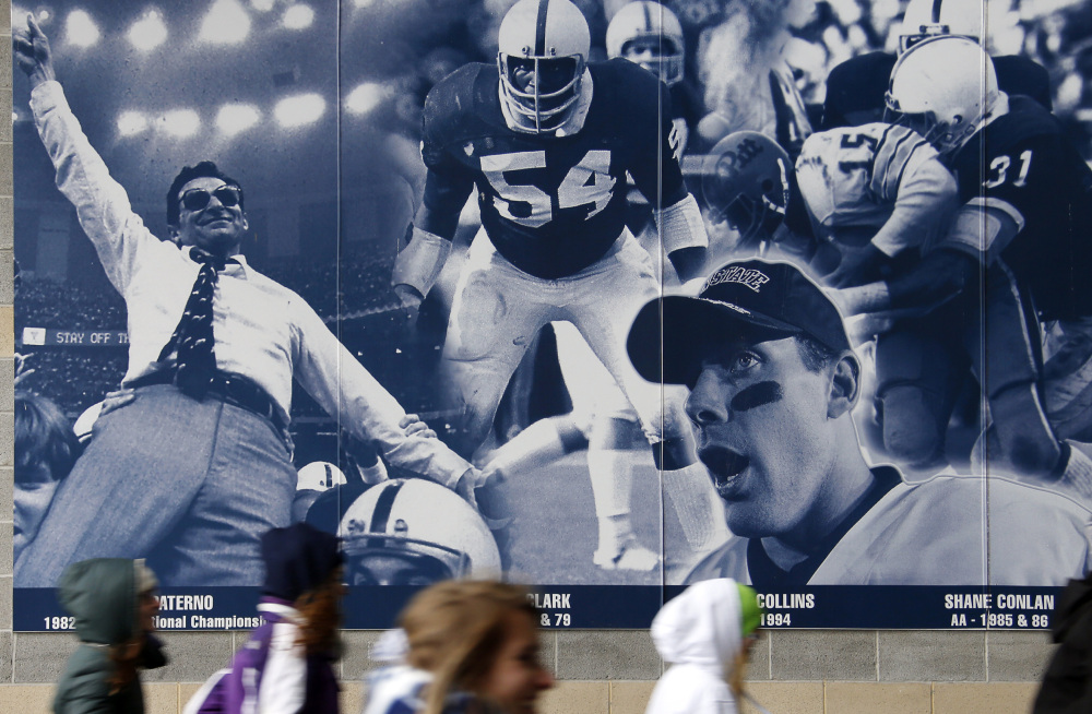 Penn State students rush into Beaver Stadium past a mural containing a photo commemorating former football coach Joe Paterno, left rear, and Penn State All-American football players. A proposed settlement would restore Penn State’s 112 football wins that were vacated two years ago in the Jerry Sandusky child molestation scandal.