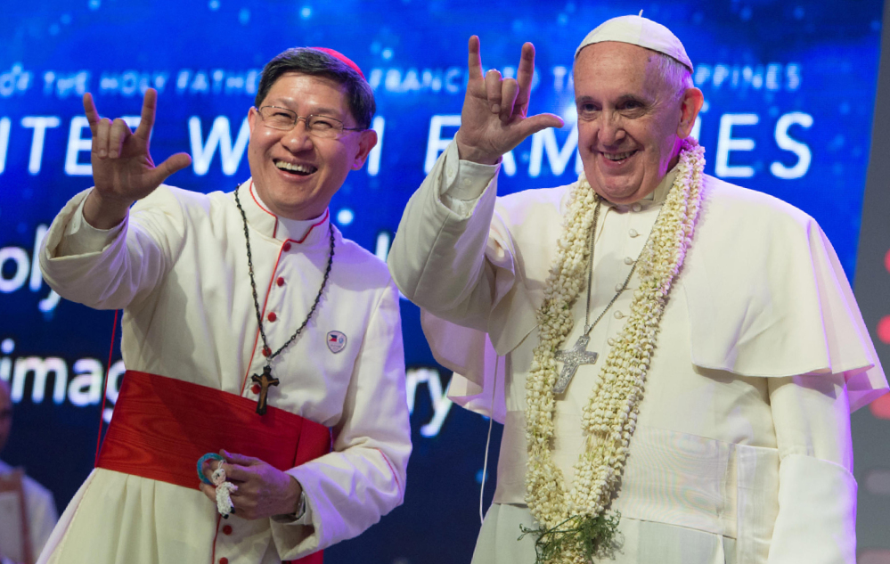 Pope Francis and Manila Archbishop Luis Antonio Tagle salute the crowd with the popular hand sign for “I love you” during a meeting with families at the Mall of Asia arena in Manila, Philippines, on Friday. 