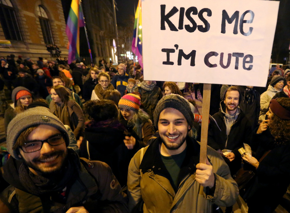 A crowd in Vienna, Austria, holds flags and signs Friday during a protest in front of a cafe where a lesbian couple was asked to leave because they were kissing.