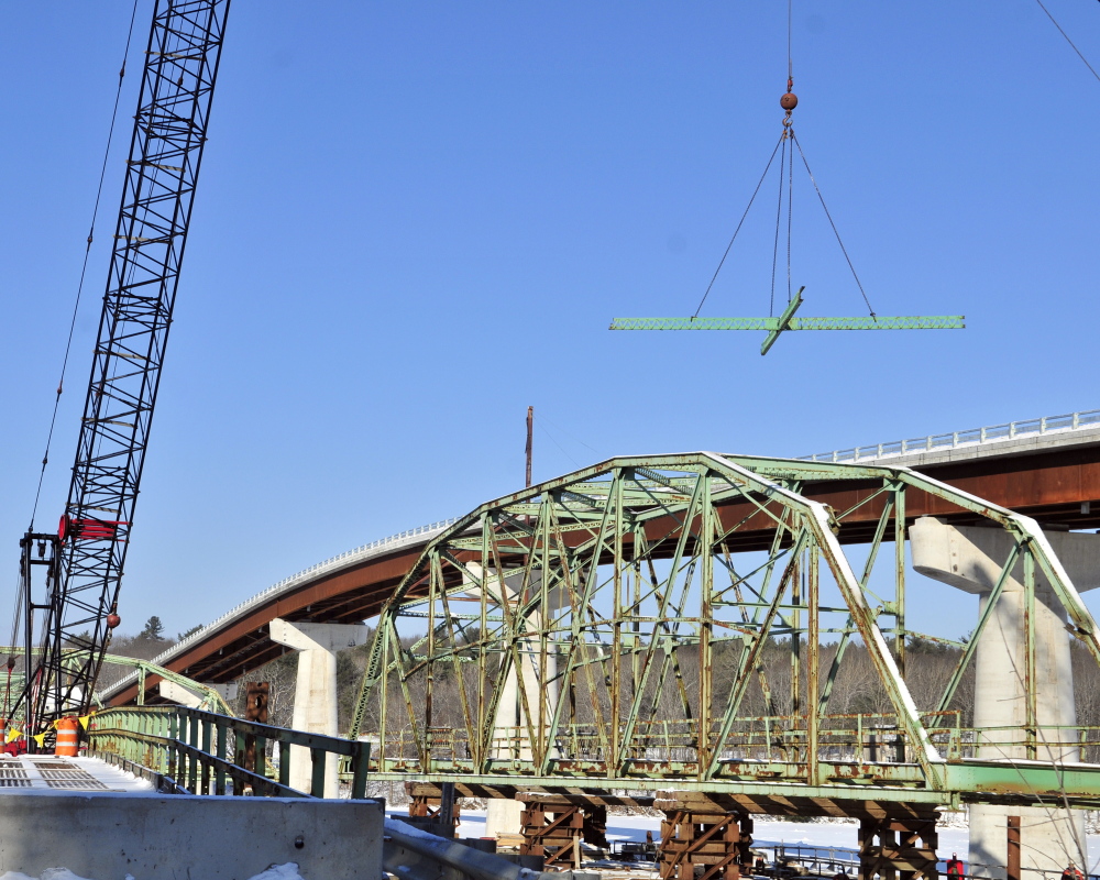 A Reed and Reed Construction crane lifts a section of beams that were just cut out as workers dismantle the old Richmond-Dresden Bridge on Friday on a barge on the Dresden shore of the Kennebec River.