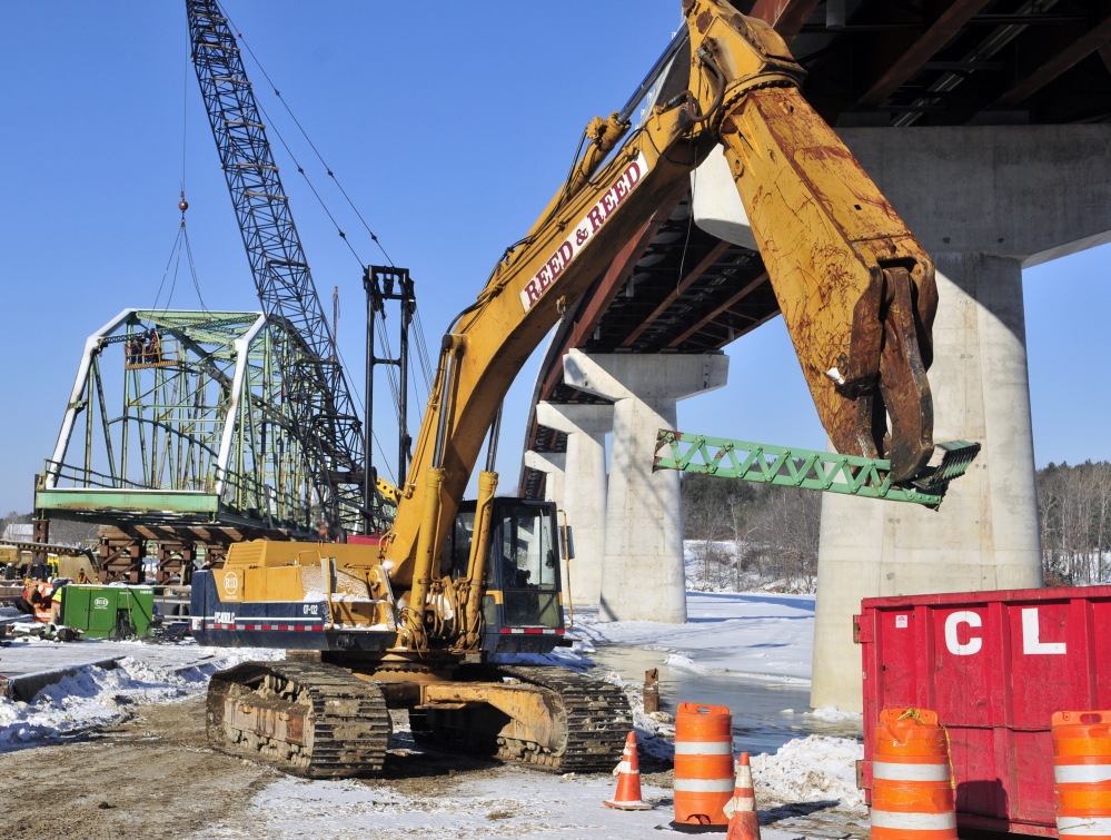 An excavator carries a piece of beam into a large container as workers dismantle the old Richmond-Dresden Bridge on Friday on a barge on the Dresden shore of the Kennebec River.
