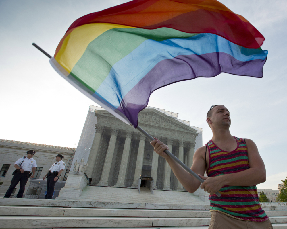 A gay rights advocate waves a rainbow flag in front of the Supreme Court in Washington. Justices will decide in April whether same-sex marriage is a constitutional right.