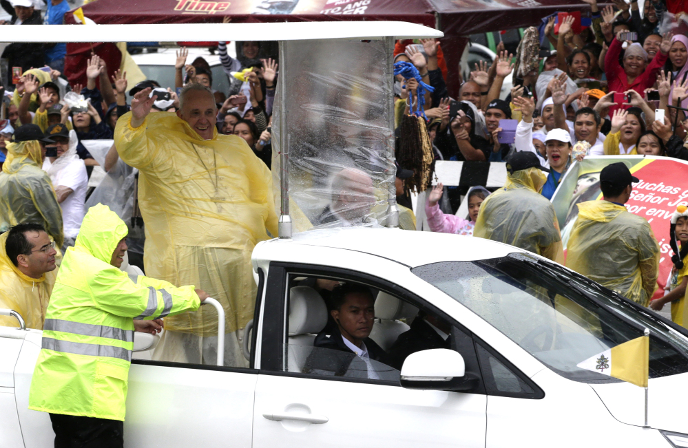 Pope Francis waves as he leaves Tacloban, Philippines, on Saturday. Francis cut short his day trip to ground zero of the devastating 2013 Typhoon Haiyan to avoid another approaching storm, but not before consoling survivors at a rain-drenched outdoor Mass.