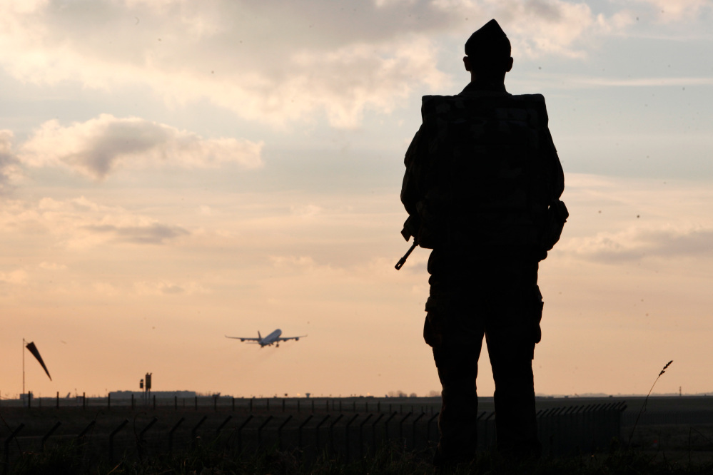 A plane takes off as a French soldier patrols at the Roissy Charles de Gaulle airport, in Roissy, north of Paris, on Saturday. France ordered 10,000 troops into the streets Monday to protect sensitive sites – nearly half of them to guard Jewish schools – as it hunted for accomplices to the Islamic militants who left 17 people dead as they terrorized the nation.