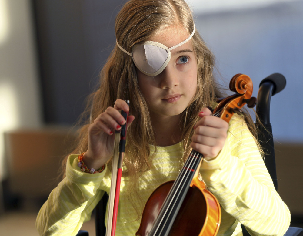 Sophie Fellows, 9, of Colchester, Vt., who is recovering from brain surgery, picks up her violin at Spaulding Rehabilitation Hospital in Boston. With the help of a music therapist, Sophie is learning to play her violin again.