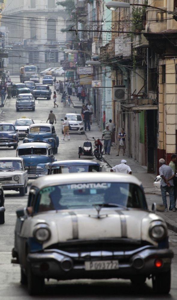 Classic American cars used as collective taxis drive along a street in Havana on Friday. The number of Americans traveling to Cuba is expected to double this year.