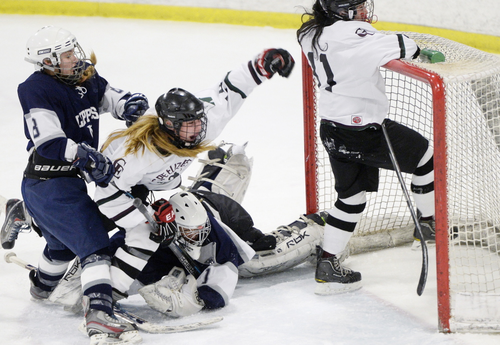 Hannah Bosworth of Cape Elizabeth/Waynflete celebrates Saturday, falling to the ice after her teammate, Kathryn Clark, right, scored during a 6-1 loss to Yarmouth/Freeport. Defending are Jenny Holmquist and goalie Hannah Williams.