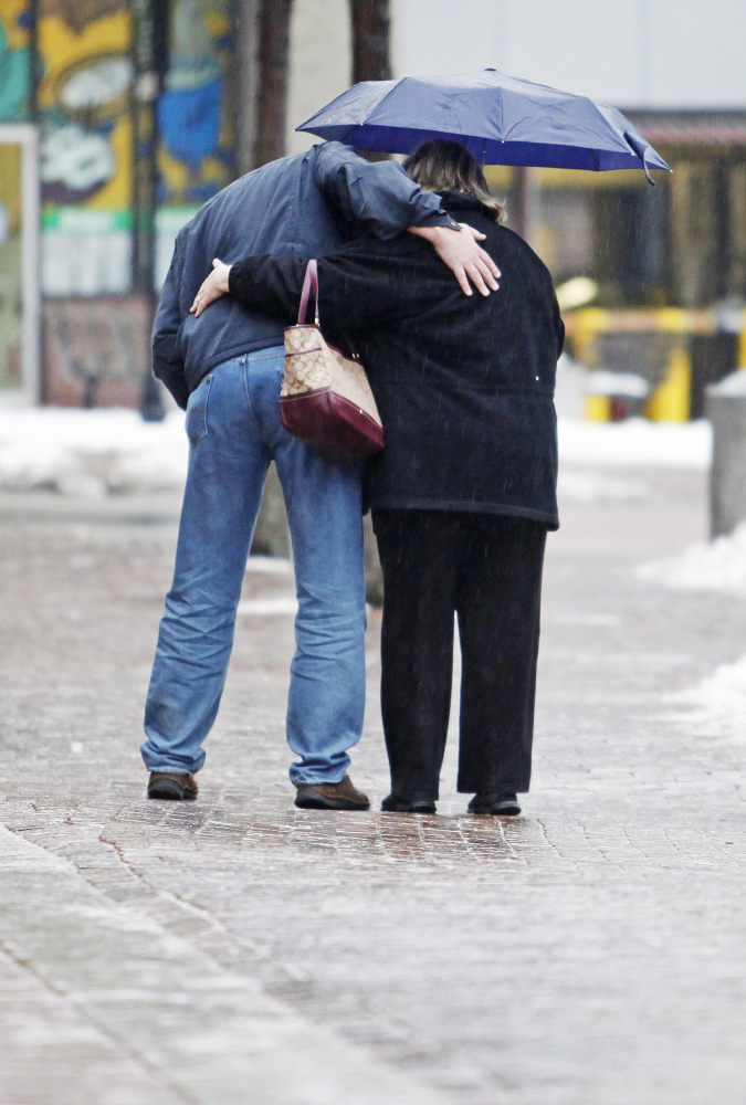 A couple hold on while making their way gingerly across icy brick sidewalks along Free Street in Portland as a cold rain falls Sunday. Jill Brady/Staff Photographer