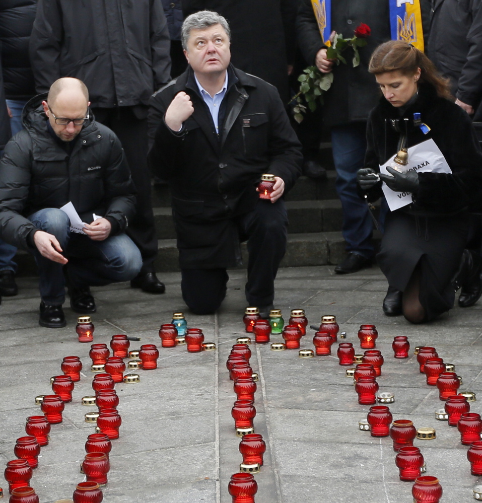 Ukrainian President Petro Poroshenko, center, his wife, Maria, and Prime Minister Arseniy Yatsenyuk pay their respects Sunday at Independence Square in Kiev in solidarity with the victims of a rocket attack that claimed 13 lives near Volnovakha.