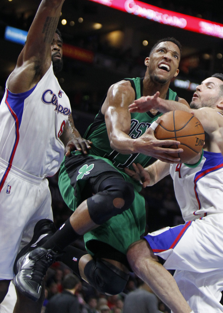Celtics guard Evan Turner splits the defense of  Los Angeles Clippers DeAndre Jordan, left, and guard J.J. Redick to take a shot during the first half of Monday’s game in Los Angeles
