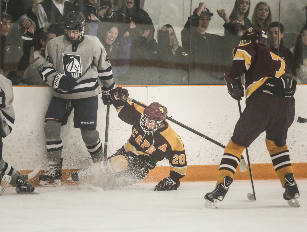 Cape Elizabeth's Curtis Guimond slides into the wall while fighting for the puck against Yarmouth's  Cooper May while teammate Matthew Riggle waits to assist . Whitney Hayward/Staff Photographer