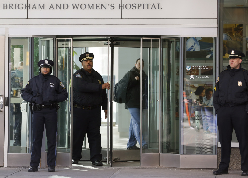 Boston police Superintendent-in-Chief William Gross, center left, walks through a revolving door as he leaves the Shapiro building at Brigham and Women’s Hospital on Tuesday in Boston.