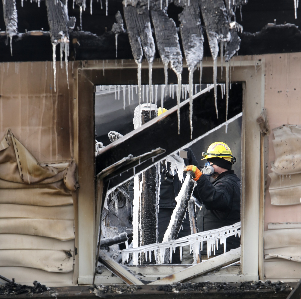 An investigator with the State Fire Marshal’s Office looks over ice-covered debris inside the Americana Motel in Old Orchard Beach. The structure was due to be removed to make way for  a parking lot.