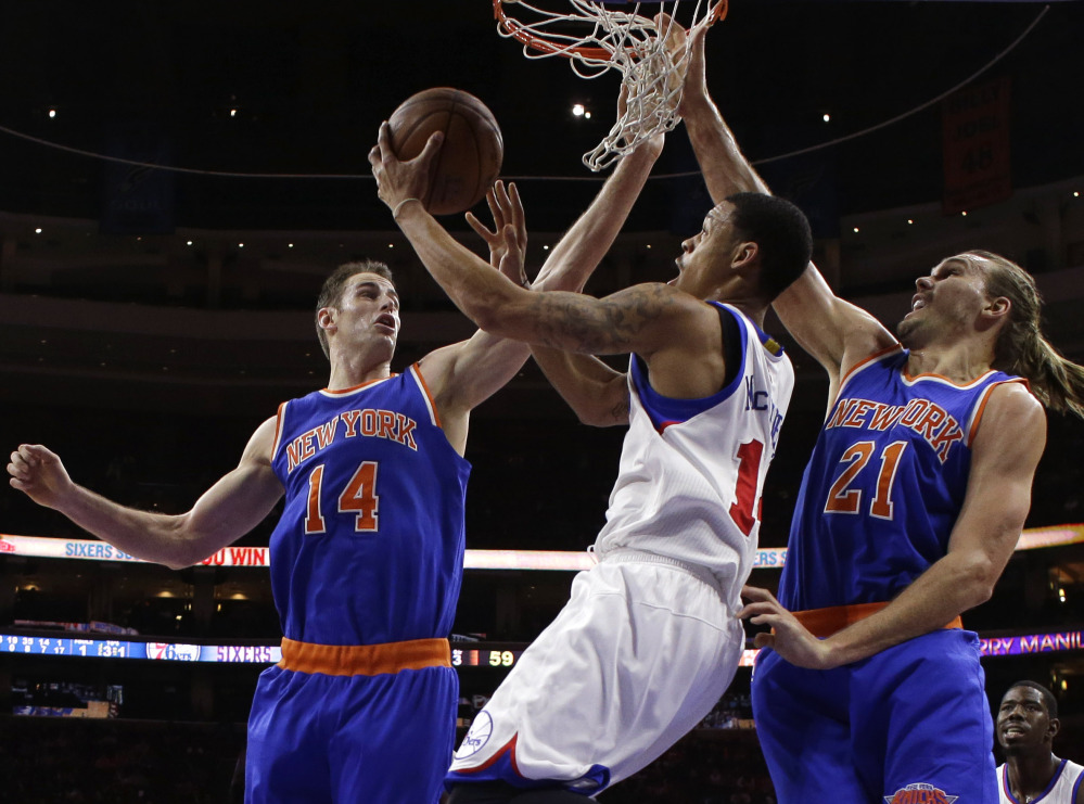 Philadelphia’s K.J. McDaniels, center, goes up for a shot between Jason Smith, left, and Lou Amundson of the Knicks in Wednesday’s game. The Knicks won their second straight, 98-91, after losing 16 straight.