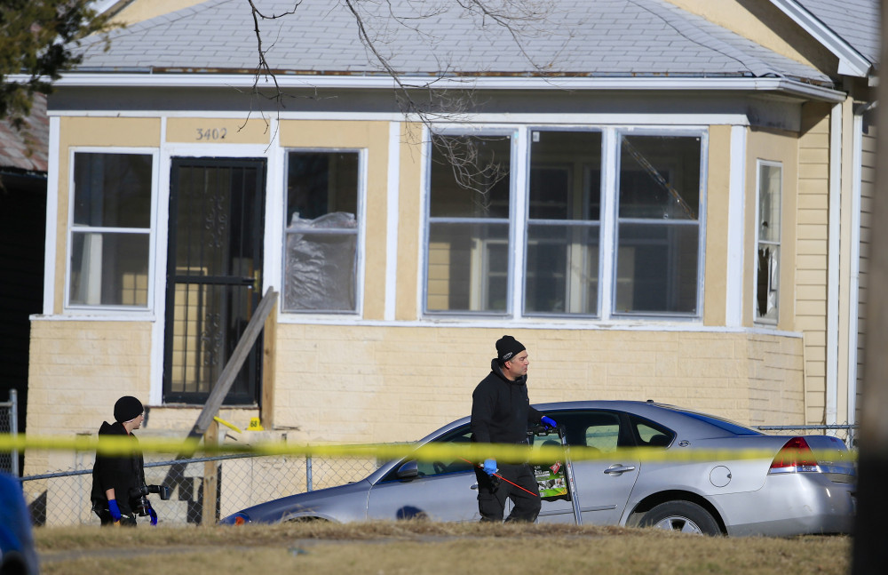 The Associated Press A crime lab investigators walk past a house where a shooting in Omaha, Neb., Saturday.