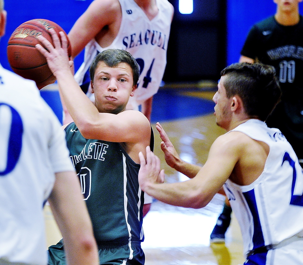 Will Burdick of Waynflete is closely guarded by Erik Hogan of Old Orchard Beach during their Western Maine Conference boys’ basketball game Saturday. Waynflete completed a season sweep of the Seagulls with a 61-56 overtime victory.
