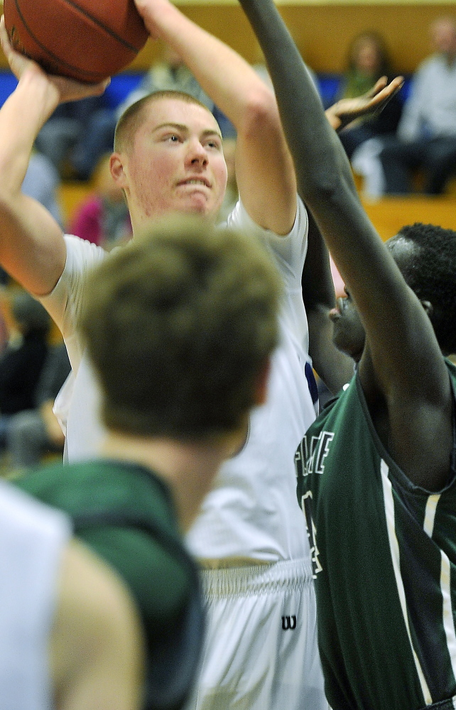 Zach Belanger of Old Orchard Beach looks for an opening to shoot against Waynflete’s Yai Deng after pulling down an offensive rebound.