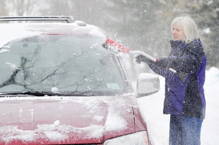 Cindy McGovern clears the snow from her van windows Saturday in the Riverside area of Portland.