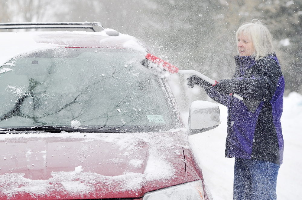 Cindy McGovern clears the snow from her van windows Saturday in the Riverside area of Portland.