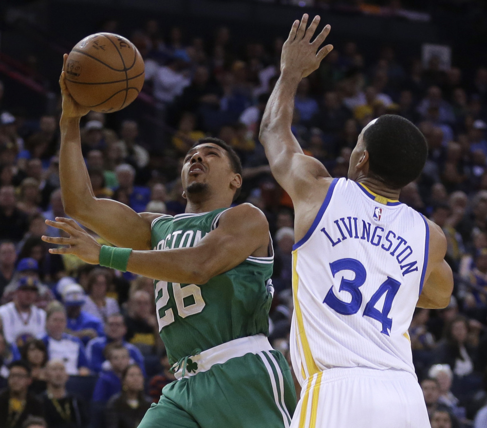 Boston’s Phil Pressey shoots over Golden State’s Shaun Livingston during the Warriors’ 114-111 win over the Celtics on Sunday in Oakland, Calif. Golden State has an NBA-best record of 36-6.