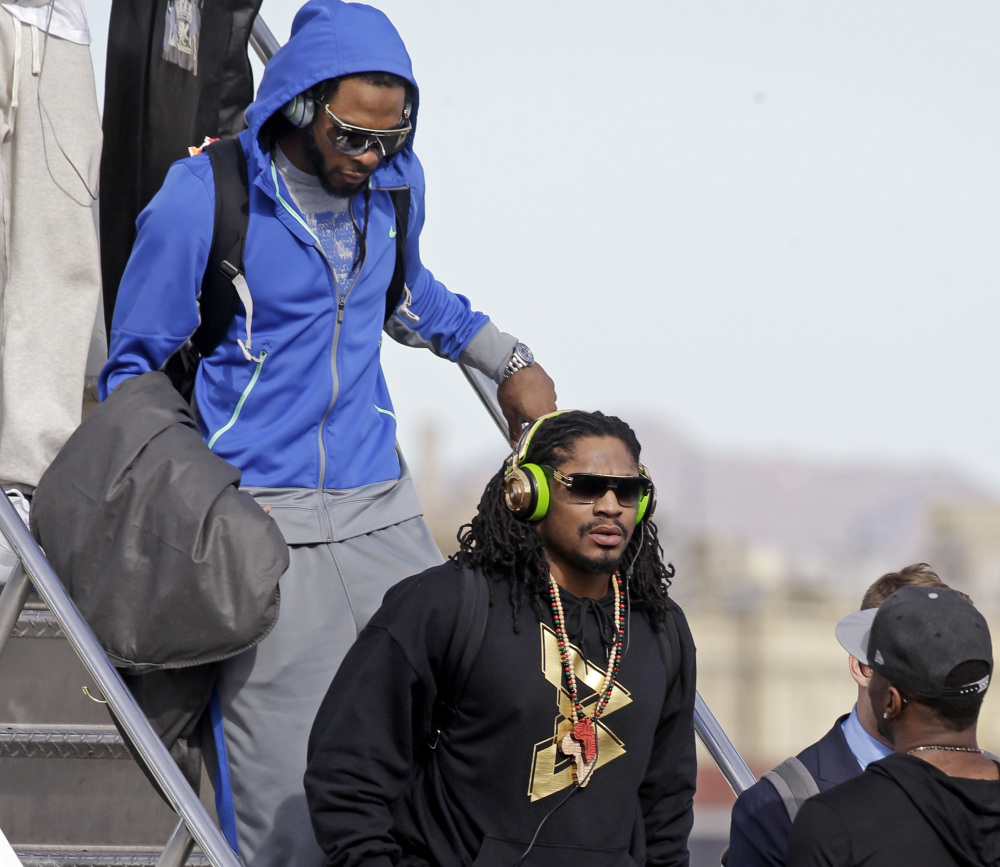 Seattle’s Richard Sherman, back, and Marshawn Lynch arrive in Phoenix on Sunday to prepare for the Super Bowl. Sherman was critical of NFL Commissioner Roger Goodell.