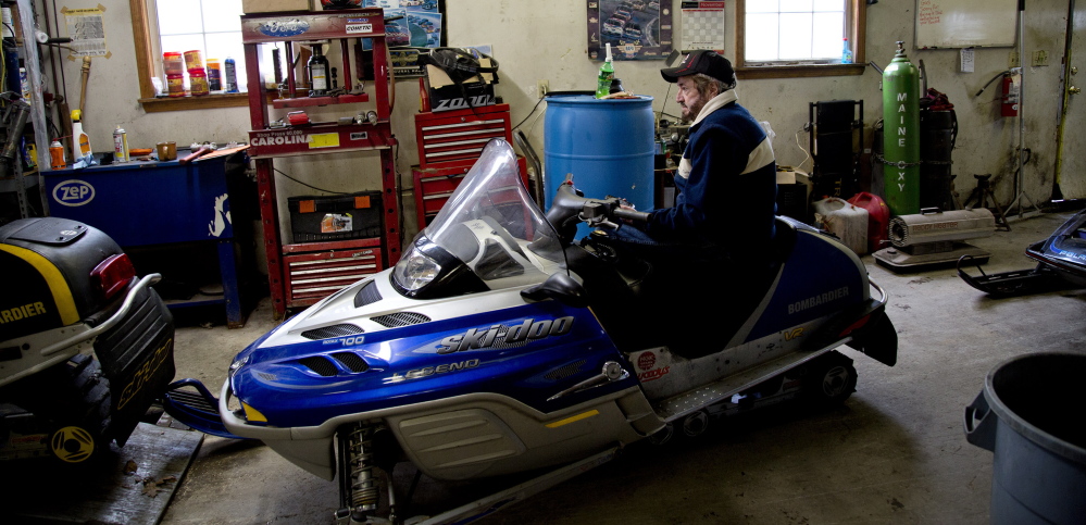 Wayne Keniston, owner of Keniston’s Auto & Snowmobile Supplies sits on a sled in his shop on the Gray Road in Falmouth on Monday. “It’s white gold for us.’ he said of Tuesday’s predicted snowfall.  Photos by Gabe Souza/Staff Photographer