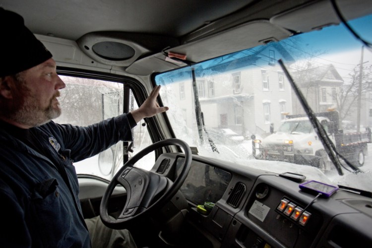 Bill Bushey, a snow plow driver with the city of Portland, waves to another driver as he works in Tuesday’s blizzard.