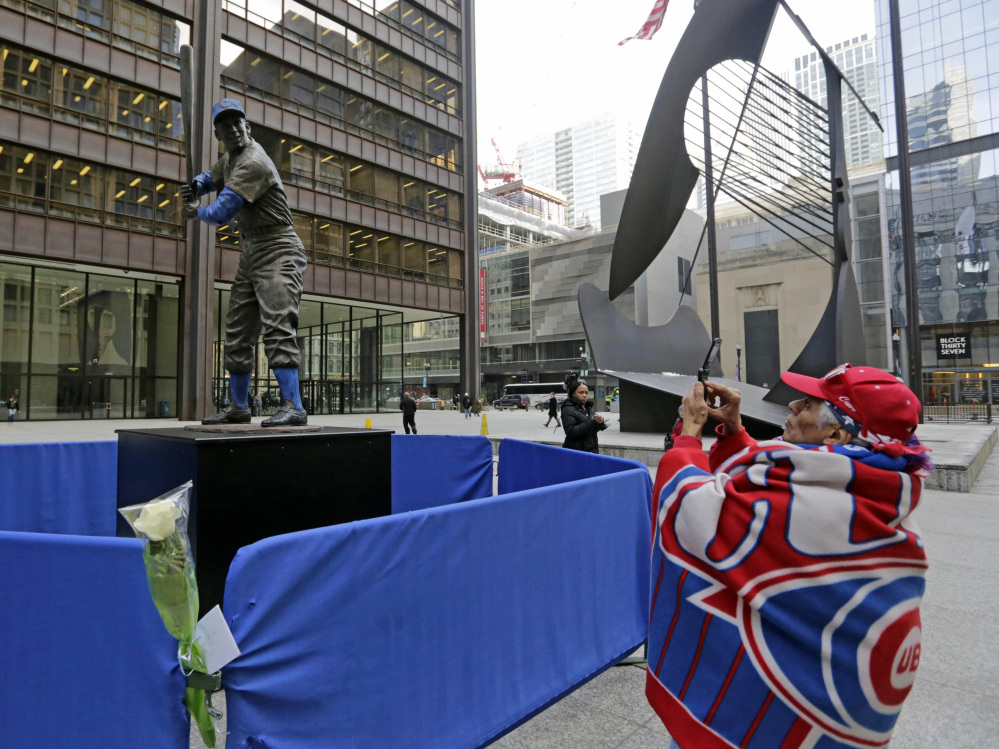 Baseball fan Geroge Valdez, 64, takes a photo of a statue of Chicago Cubs Hall of Famer Ernie Banks that was placed next to the Picasso statue in Daley Plaza, as baseball fans get their first chance to pay their respects, in Chicago.