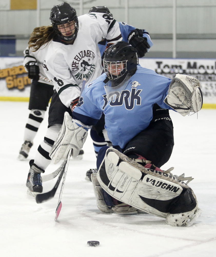 Sophia Stephens of York makes a save Wednesday as Hannah Bosworth of Cape Elizabeth/South Portland/Waynflete looks to slip in a rebound during their girls’ hockey game in Portland. The teams played to a 1-1 tie.