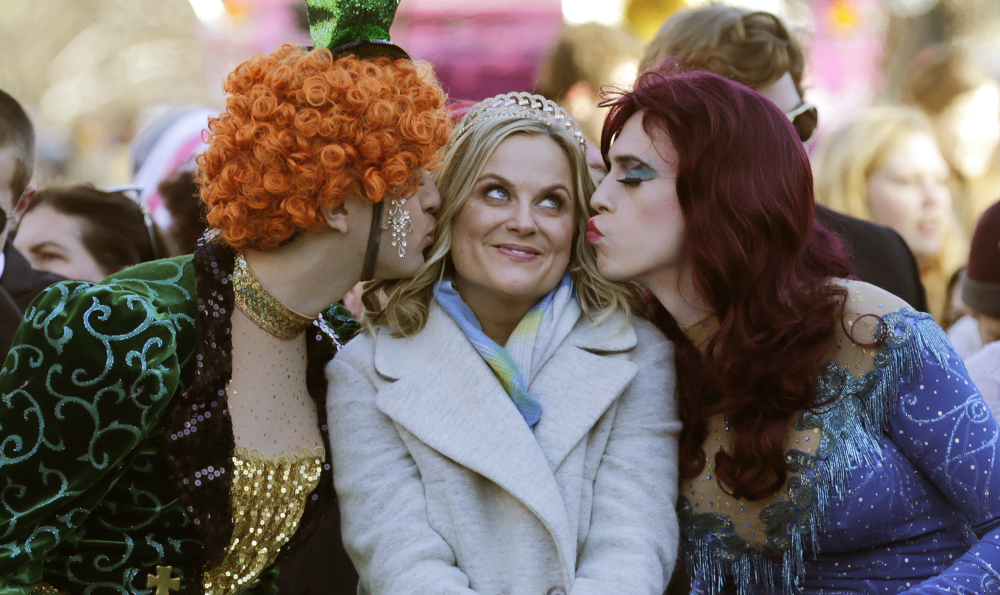 Amy Poehler is kissed by Jason Hellerstein, left, and Sam Clark, who are dressed in drag, in Cambridge, Mass.