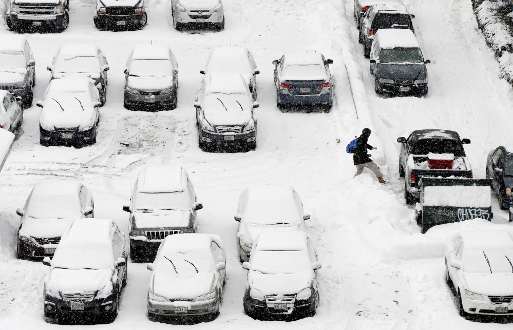 PORTLAND, ME - JANUARY 30: A man carefully steps over a snowbank in a snow covered parking lot on Free St. in Portland during Friday’s snowfall January 30, 2015. (Photo by)
