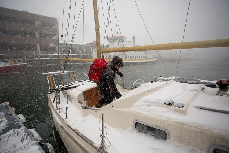 JAN. 27: Jack Marrie enters his 30-foot fiberglass ketch Rime, where he lives year-round, during the Tuesday blizzard. Marrie said he did nothing special to prepare for the storm, and that winter can actually be easier than summer when it comes to living on a boat.