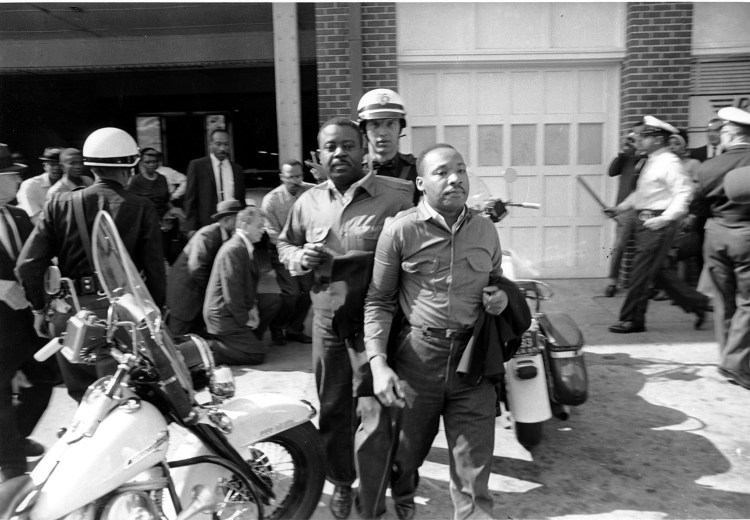 The Rev. Ralph Abernathy, left, and Rev. Martin Luther King Jr., right, are taken by a policeman as they led a line of demonstrators into the business section of Birmingham, Alabama, on April 12, 1963.
