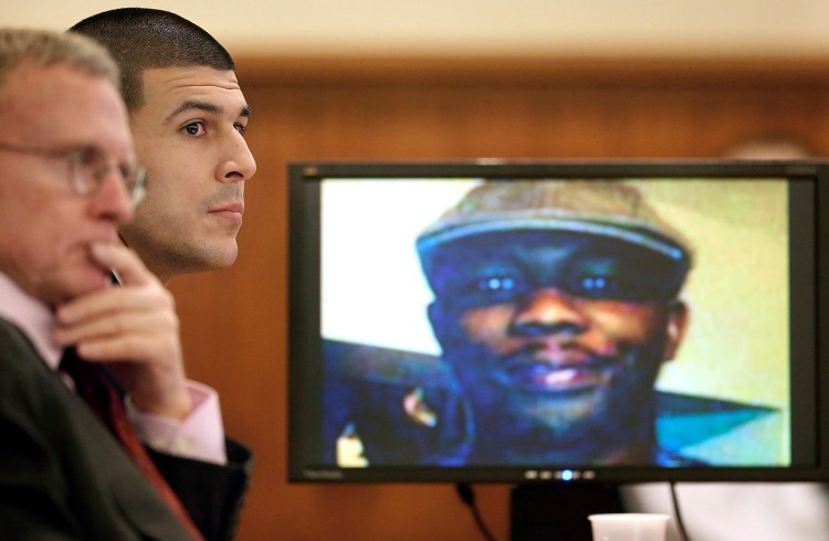 Former New England Patriots football player Aaron Hernandez, center, listens during his murder trial Thursday,in Fall River, Mass., while an image of Odin Lloyd is displayed on a monitor. Hernandez is charged with killing Lloyd, 27, a semiprofessional football player, in June 2013. The Associated Press