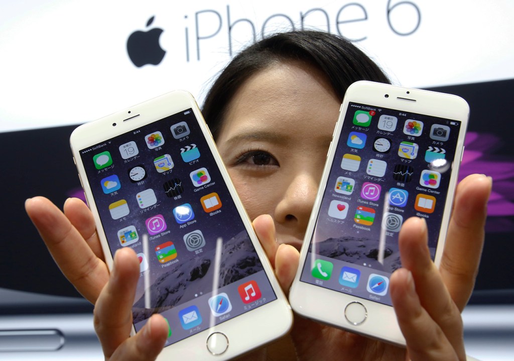 A customer shows off the new Apple iPhone 6 and 6 Plus at a store in Tokyo in this Sept. 19, 2014,  photo. Overall, Apple reported $74.6 billion in sales and $18 billion in profits for the December quarter, a year-over-year increase of 30 percent and 38 percent respectively. The Associated Press