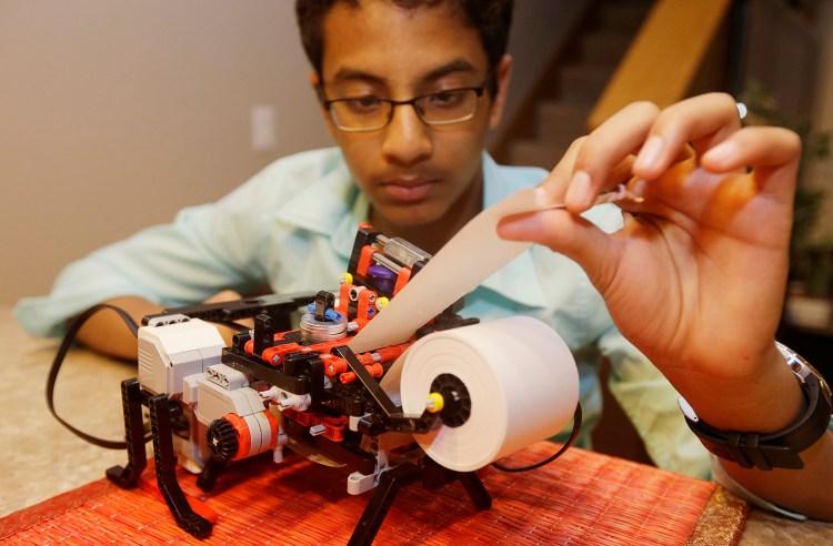Shubham Banerjee  works on his Lego robotics Braille printer prototype at home in Santa Clara, Calif. He aims to develop a low-cost printer based on the prototype. Last month, tech giant Intel Corp. invested in his startup, Braigo Labs. The Associated Press