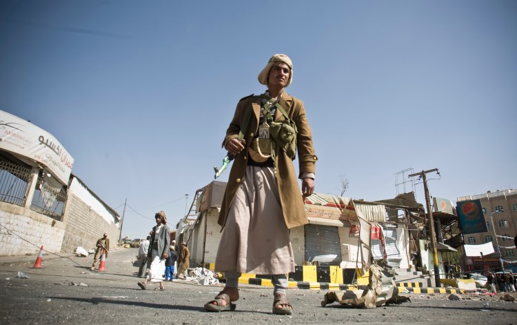 A Houthi Shiite Yemeni stands guard in front of a building damaged during clashes near the presidential palace in Sanaa, Yemen, Tuesday. The Associated Press