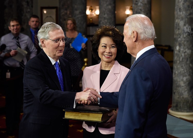 Vice President Joe Biden shakes hands with Senate Majority Leader Mitch McConnell of Kentucky after Biden administered the Senate oath during a re-enacted swearing-in ceremony Tuesday in Washington. McConnell's wife, former Labor Secretary Elaine Chao, is at center.