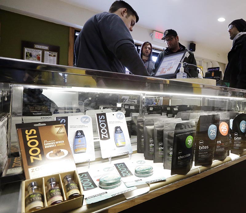 Cannabis City clerk John Golby, left, helps customers looking over a display of marijuana products at the shop in Seattle.