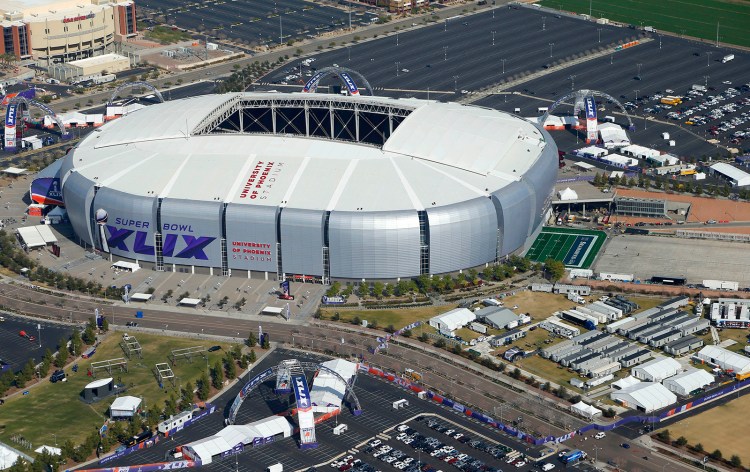 The playing field for the NFL Super Bowl XLIX football game is rolled into the University of Phoenix Stadium Wednesday in Glendale, Ariz.  The Associated Press