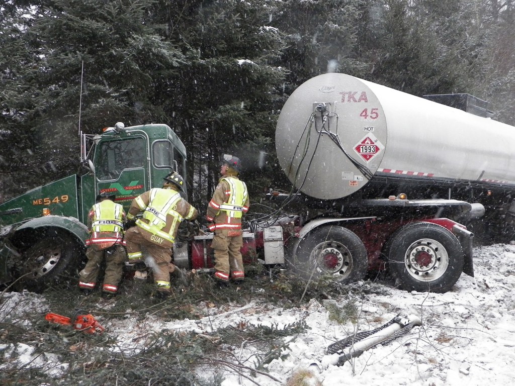 Emergency personnel work on an oil tanker truck Friday after it slid off the Maine Turnpike around mile marker 28 southbound in Arundel.