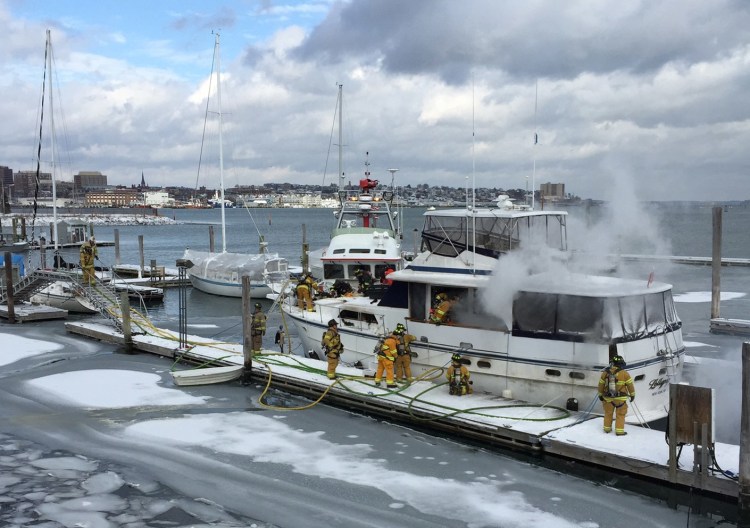 Firefighters work to extinguish a fire aboard a boat at South Port Marine in South Portland on Friday.