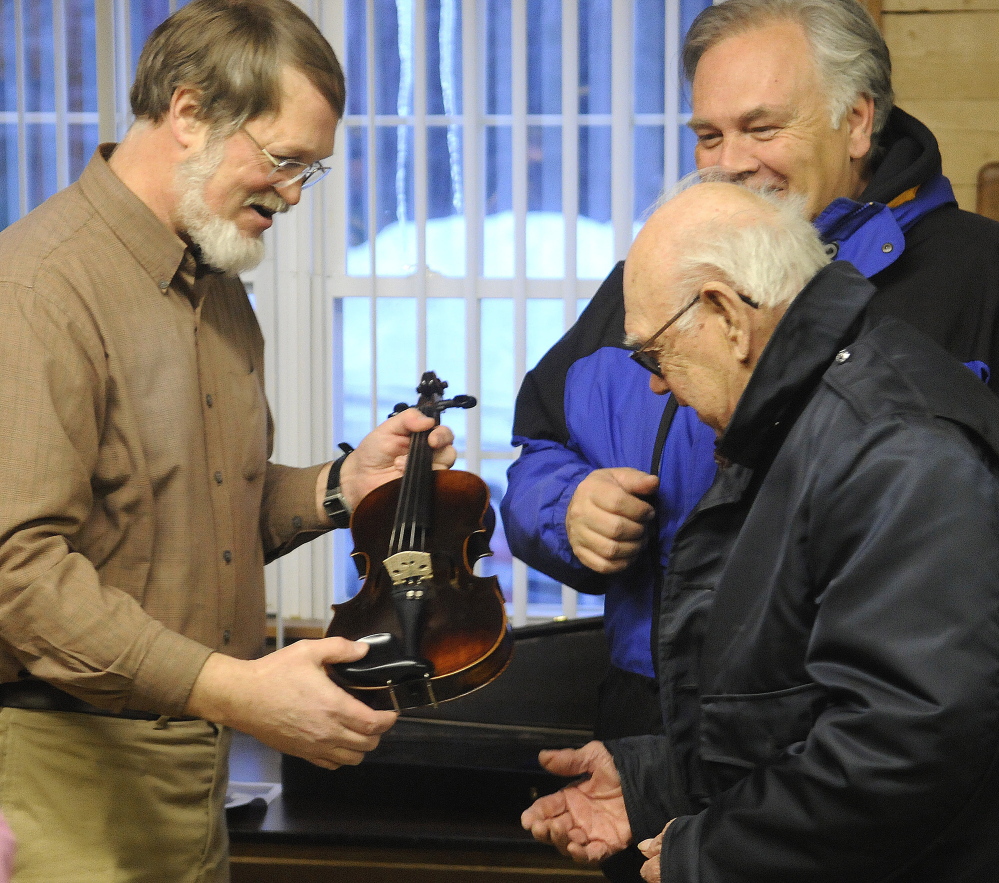 Nate Saunders hands a violin he restored recently to its owners, Roger C. Badershall, right, and his son, Roger E. Badershall, on Tuesday at American Legion Fitzgerald-Cummings Post 2 in Augusta.