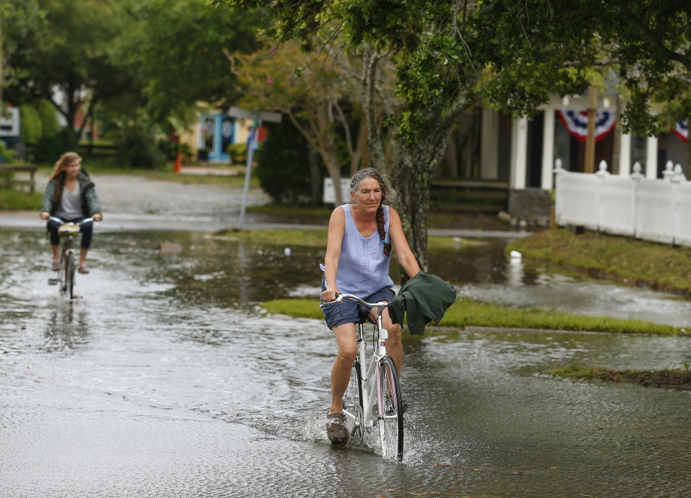 Bicyclists navigate a flooded street after Hurricane Arthur passed through Manteo, a town on North Carolina’s Roanoke Island. The state’s Outer Banks will see more frequent destructive tidal flooding as sea levels rise over the next 30 years, several studies say.